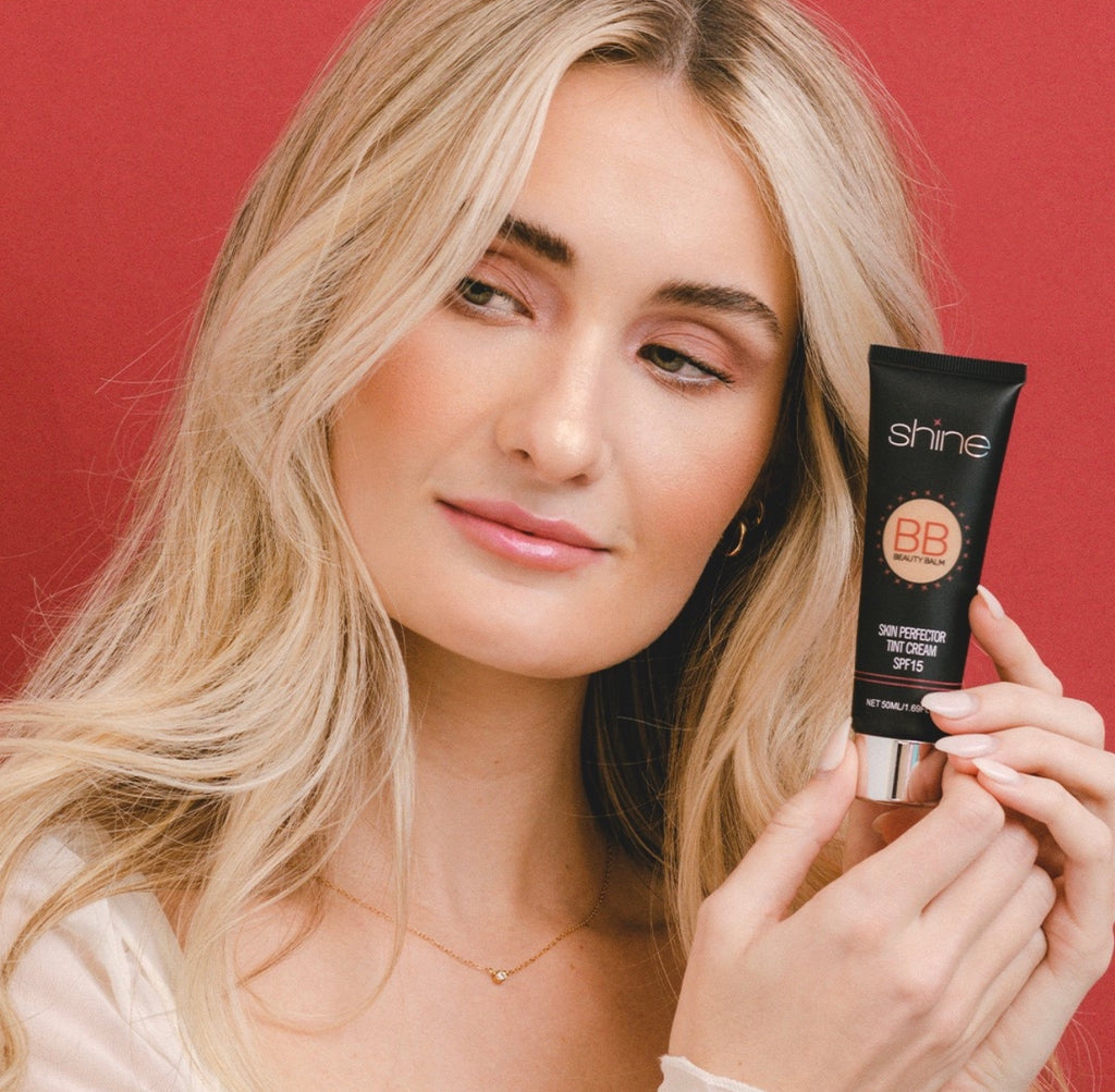 Beautiful woman blonde hair holding Shine Cosmetics BB Cream on a red background